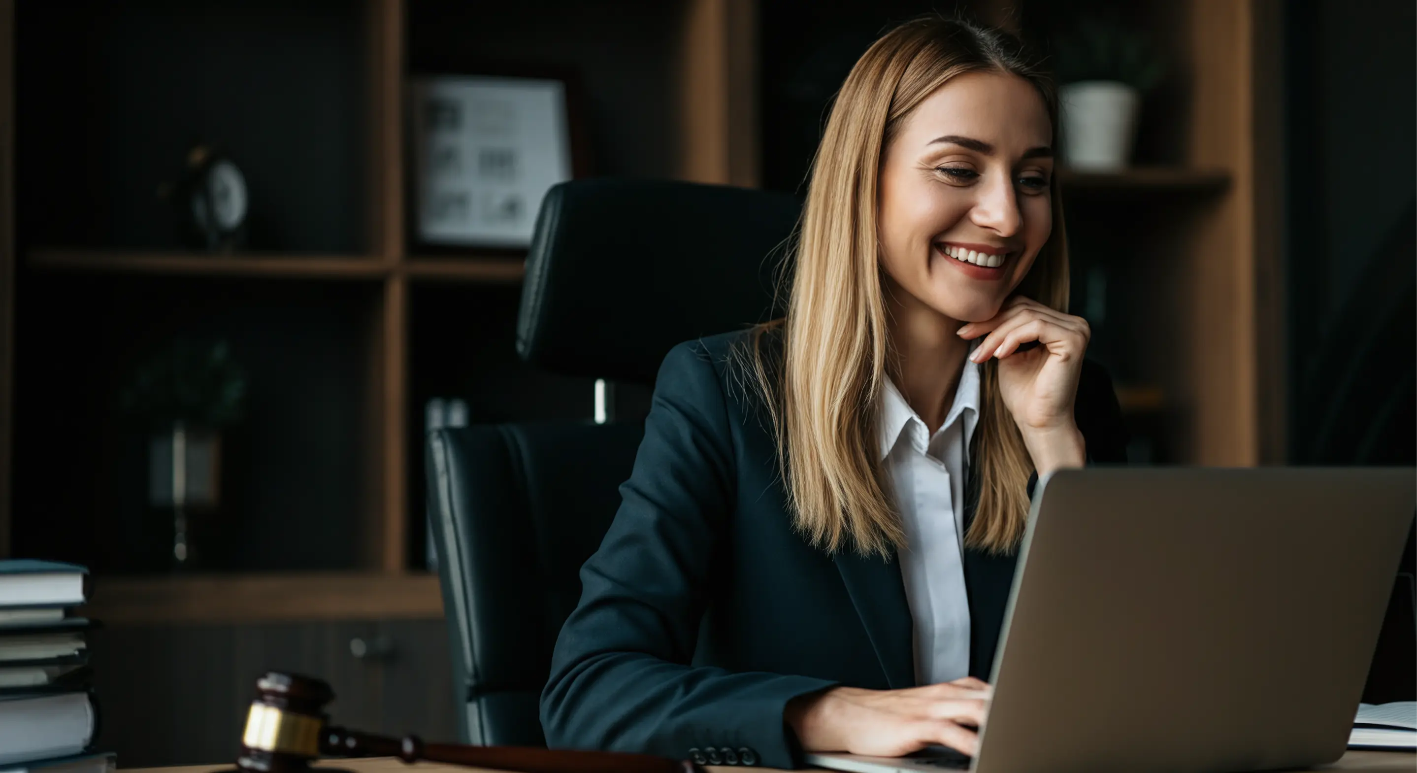 Profissional de atendimento ao cliente sorrindo enquanto responde chamadas no computador em um ambiente corporativo